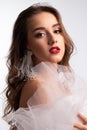 Close up portrait. Young beautiful girl with perfect make up in white veiling dress. Studio shot