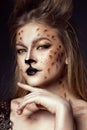 Close up portrait of young beautiful grey-eyed model with artistic leopard make-up and brushed up hair looking straight