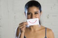 Close up portrait of young beautiful and happy hispanic woman smiling with paper in mouth