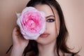 Close-up portrait of young beautiful sexy woman with pink rose near face. Royalty Free Stock Photo