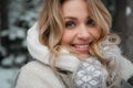 Close up portrait of a young beautiful smiling blonde woman in a snowy forest in winter Royalty Free Stock Photo