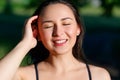 Close up portrait of a young beautiful smiling happy brunette girl in outdoor Park on a Sunny summer day correcting hand loose Royalty Free Stock Photo