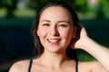 Close up portrait of a young beautiful smiling happy brunette girl in outdoor Park on a Sunny summer day correcting hand loose Royalty Free Stock Photo