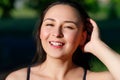 Close up portrait of a young beautiful smiling happy brunette girl in outdoor Park on a Sunny summer day correcting hand loose Royalty Free Stock Photo