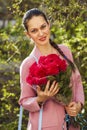 Portrait of a young beautiful woman with a bouquet of red roses in spring park Royalty Free Stock Photo