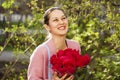 Portrait of a young beautiful woman with a bouquet of red roses in spring park Royalty Free Stock Photo