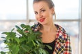 Close-up portrait of a young beautiful woman, holding decorative plant, smiling, looking at camera Royalty Free Stock Photo