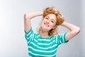 Close-up portrait of a young, beautiful woman with red curly hair in a summer dress with strips of blue in the studio on a gray ba