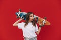 Close up portrait of a young beautiful woman skateboarder holding her colorful long board behind her head while standing on an Royalty Free Stock Photo