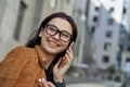 Close up portrait of a young beautiful woman wearing eyeglasses talking on smartphone with friend, looking aside and Royalty Free Stock Photo