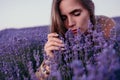 Woman lavender field. Happy carefree woman in beige dress and hat with large brim smelling a blooming lavender on sunset Royalty Free Stock Photo