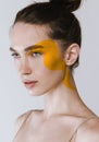 Close-up Portrait Of Young Beautiful Woman With Yellow Drawing Element On Face Isolated On Grey Background. Festival