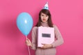 Close up portrait of young beautyful darkhaired woman with gift and blue balloon posing  over background. Lady dresses Royalty Free Stock Photo