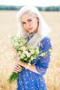 Close up portrait of a young blonde girl with a bouquet of field daisies