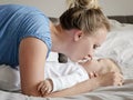 Close-up portrait of young happy mother with her baby on bed in bedroom. - image