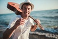 Portrait of a young casual man with guitar on his shoulder on the beach Royalty Free Stock Photo