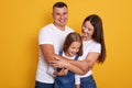 Close up portrait of young Caucasian family.Father, mother and charming daughter. Parents hugging little cute child dressed denim Royalty Free Stock Photo