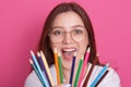 Close up portrait of young caucasian girl with staright hair holding colored pencils while looking directly at camera and Royalty Free Stock Photo