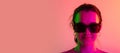 Close-up portrait of young caucasian girl in sunglases isolated over gradient studio background in neon lights. Flyer Royalty Free Stock Photo