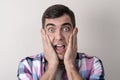 Close-up portrait of young Caucasian man with shocked face holding his cheeks with his mouth open Royalty Free Stock Photo