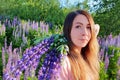 Close-up portrait of young caucasian woman with long red hair, against the background of greenery in  lupin`s field. Royalty Free Stock Photo