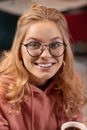 Close up portrait of young Caucasian woman looking through the camera and smiling beamingly.