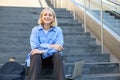 Close up portrait of young cheerful woman, looking confident at camera, sitting on street, urban stairs with laptop Royalty Free Stock Photo