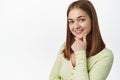 Close up portrait of young confident girl look intrigued, interested in smth, touch chin and smile thoughtful, looking