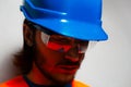 Close-up portrait of young construction worker engineer wearing safety equipment; blue hard hat and transparent goggles. Royalty Free Stock Photo