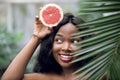 Close up portrait of young emotional beautiful afro american woman with grapefruit in her hands, looking out of green Royalty Free Stock Photo