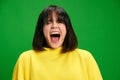 Close-up portrait of young emotional brunette woman with short haircut in white shirt loudly shouting against vibrant Royalty Free Stock Photo