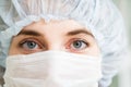 Close-up portrait of young female surgeon doctor or intern wearing protective mask and hat