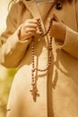 Close up portrait of young girl holding wooden rosary and praying. Vertical image Royalty Free Stock Photo