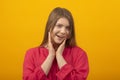 Close up portrait of young girl smiling sweetly and make eyes. Young woman in red shirt on an yellow background Royalty Free Stock Photo