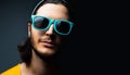 Close-up portrait of young guy wearing cyan sunglasses on black background with copy space. Royalty Free Stock Photo