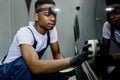 Close up portrait of young handsome African worker of auto repair and detailing service, applying professional solid wax