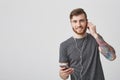 Close up portrait of young handsome cheerful ginger bearded man with tattooed arm in casual modern clothes smiling with Royalty Free Stock Photo