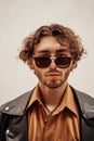 Portrait of a young man with curly hair posing in a bright studio looking self-assured in leather coat Royalty Free Stock Photo