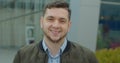 Close-up portrait of young handsome man standing outdoors alone smiling looking at camera. Beautiful people, city Royalty Free Stock Photo