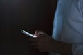 Portrait of young handsome man using smart phone in hand on dark background