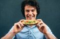 Close-up portrait of young happy man eating a healthy hamburger. Handsome man in a fast food restaurant eating a hamburger Royalty Free Stock Photo