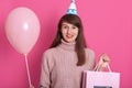 Close up portrait of young happy woman in birthday hat, dresses stylish rosy sweater, looking at camera, posing  over pink Royalty Free Stock Photo