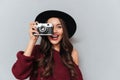 Close-up portrait of young hipster brunette woman looking through the viewfinder of retro photocamera