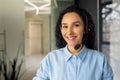 Close-up portrait of young Hispanic business woman smiling at workplace and looking at camera, online customer service Royalty Free Stock Photo