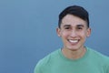 Close up portrait of a young Hispanic teenager man looking at camera with a joyful smiling expression, against a blue background