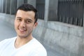 Close up portrait of a young hispanic teenager man looking at camera with a joyful smiling expression, against urban background