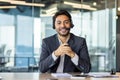 Close-up portrait of a young Indian man sitting in the office at the desk wearing a headset, smiling and talking to the Royalty Free Stock Photo