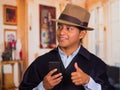 Close up portrait of young indigenous man wearing hat and poncho using cell phone Royalty Free Stock Photo