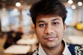 Close up portrait of young male indian freelancer in fast food cafe, handsome head of asian man wear in shirt at comfortable