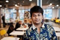 Close up portrait of young male indian freelancer in fast food cafe, handsome head of asian man wear in shirt at comfortable